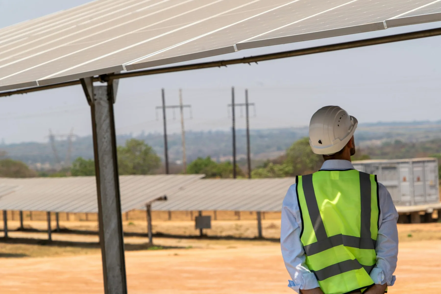 Engineer in a hard hat inspecting a solar array